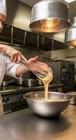 Chef whisking batter in a stainless steel bowl under warm industrial lighting photo