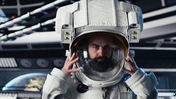 Portrait of smiling astronaut holding helmet inside space station, preparing for planetary mission outside. Happy starship crew member beginning landing procedures on solar system planet video