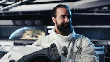 Portrait of smiling astronaut holding protection helmet doing human expansion in space. Jolly man in starship prepares for expedition supporting long term mankind survival, camera B video