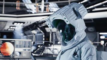 Female astronaut in spacesuit checks wrist device inside spacecraft doing human expansion in space. Starship crew member prepares for operations supporting long term mankind survival, camera B video