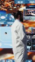 Vertical Young medic interacting with virtual health technology for telemedicine, connected systems and smart diagnostics in delivering global healthcare solutions. Biotechnology development. Camera B. video