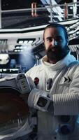 Vertical Astronaut inside futuristic spaceship checking red planet journey analytics during routine mission check. Space station cosmonaut using device, standing near monitor showing Mars expedition metrics video