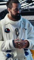 Vertical Astronaut reading mission plan on tablet before stepping out for scheduled operations outside space station. Cosmonaut checks analytics on device, preparing to leave after landing on planet, camera B video