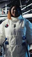 Vertical Astronaut inside high tech spacecraft checking red planet summary analytics during routine mission check. Orbit station cosmonaut using device, standing near monitor showing Mars data video