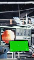 Vertical Astronauts in advanced technology spacecraft using green screen monitor updating flight log during routine mission check. Orbit station crew colleagues looking at system diagnostics on mockup display video