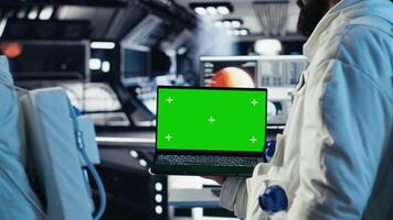 team van astronauten controle menselijk uitbreiding in ruimte missie logboeken Aan groen scherm laptop. kosmonauten gebruik makend van chroma sleutel notitieboekje gedurende mensheid overleving expeditie, camera b video
