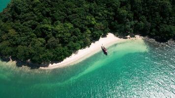 Drone shot of sailboat in secluded tropical bay with calm waters, breathtaking island getaway featuring boats resting in tranquil lagoon with golden sand and palm trees nearby. video