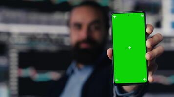 Professional man holds phone with green screen and explores strategy planning with insight and financial data in workspace. Representing modern business intelligence and productivity. Camera A. video
