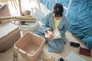 Student asian woman organize room sitting on the floor surrounded by boxes and other items photo