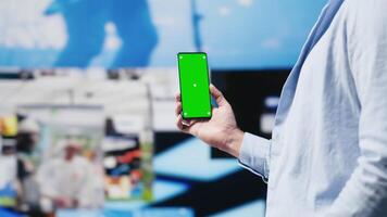 Young adult holds phone with chroma key screen and connecting on socials, using his imagination and modern e commerce skills to connect with people online. Entertainment. Camera A. video