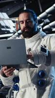Vertical Jolly astronaut waves hand during videocall with Earth command center, documenting results from space experiments. Cosmonaut salutes ground center team, sharing research observations, camera B video