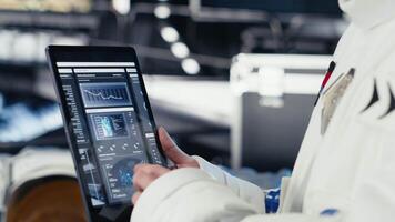 Close up of cosmonaut studying mission plans on device before expedition, preparing for future of mankind. Astronaut in spaceship explores planet to support human life beyond Earth video