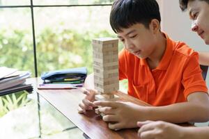 Asian father and son playing wood blocks game Carefree kid playing wood blocks game building constructor from blocks with father. photo