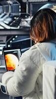 verticale femelle astronaute dans scaphandre chèques Humain expansion dans espace mission Les données sur tablette à l'intérieur vaisseau spatial. femme dans vaisseau prépare pour expédition justificatif longue terme humanité survie, caméra une video