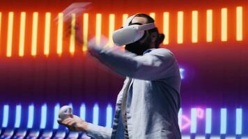 Cool modern guy showcasing artistic vibes with his virtual reality glasses, surrounded by colorful neon lights in a cyberpunk atmosphere for entertainment. Nightlife minimalism. Camera A. video
