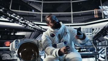 Astronaut doing hand gestures while taking selfies with smartphone inside space station during exploration mission. Man takes pictures with mobile phone during cosmic expedition, camera B video