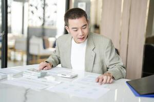 a man in a suit sitting at a table with papers and a laptop photo