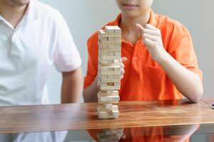 a boy and a man playing with wooden blocks on a table photo