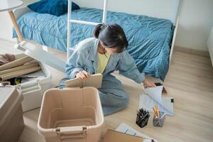 Student asian woman sitting on the floor with boxes and papers photo