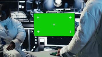 astronaut toezicht houden systeem diagnostiek Aan groen scherm Scherm, pratend naar collega gedurende ruimte missie. samenwerken kosmonauten gebruik makend van chroma sleutel toezicht houden op gedurende mensheid overleving expeditie, camera b video
