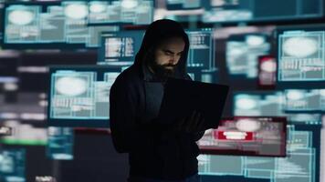 Conceptual representation of cyber crime with male hacker exploiting system vulnerability, using programming technique and surveillance to override digital defenses and leak information. Camera A. video