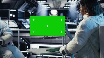 Astronauts checking human expansion in space mission logs on isolated screen monitor. Teamworking cosmonaut looking at mockup display during mankind survival expedition, camera B video