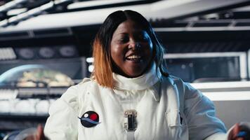 Jolly astronaut waves hand during videocall with Earth command center, documenting results from space experiments. Cosmonaut salutes ground center team, sharing research observations, camera B video