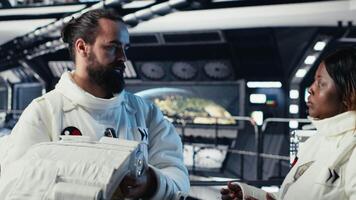 Astronaut putting helmet on before stepping out for scheduled operations outside space station, doing fist bump with colleague. Cosmonaut preparing to leave starship after landing on planet, camera B video