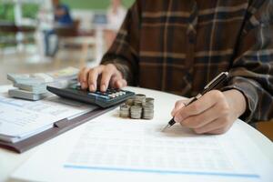 Businessman Saving money analyzing investment charts and pressing calculator buttons over documents. Accounting Concept. photo