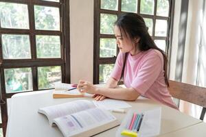 Asian girl student doing exam hand holding pencil writing answer in university classroom education high school or university student taking notes while preparing for exam photo