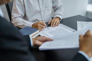 two lawyer sitting at a table with papers and pens. photo