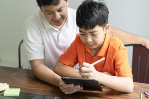 a man and boy sitting at a table with a tablet photo