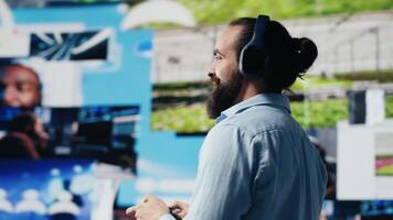 Casual man with headphones admire social media visuals and user interface elements, highlighting the power of communication and online entertainment. Web digitalization. Camera A. video