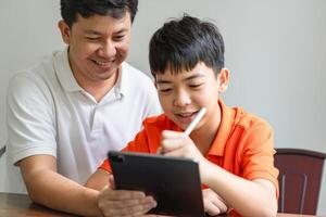 a man and a boy are sitting at a table with a tablet photo