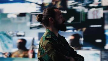 Young veteran reviewing battlefield data in a high tech command center, ensuring war planning through tactics and geopolitics details. Modern military environment focused on protection. Camera A. video
