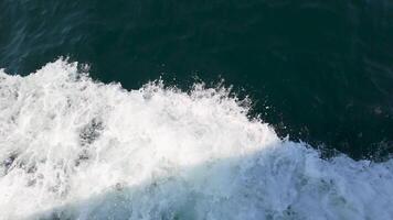 Waves crashing against the boat as it sails through deep blue waters near the coast on a sunny day video