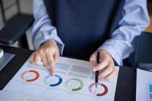 a person is holding a pen and pointing to a chart photo