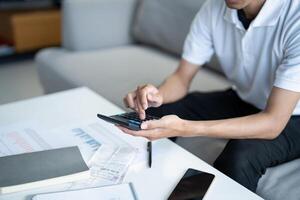 a man is using a calculator while sitting on a couch photo