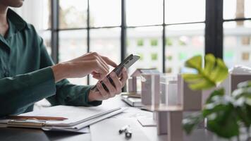 a man is using his phone while sitting at a desk photo