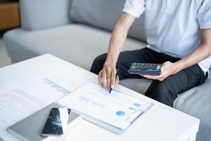 man using calculator and pen to calculate the financial situation photo