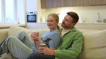 Relaxed loving couple hugging on couch while sipping tea. Heartfelt connection, close cozy bonding video