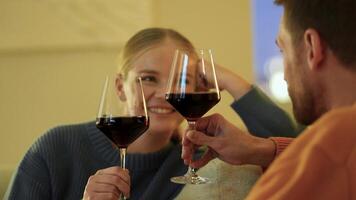 Shy romantic woman drinks wine on date with boyfriend on sofa, look lovingly in evening conversation video