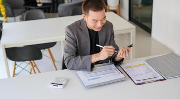 a man in a suit is looking at his phone while sitting at a desk photo