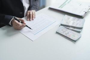 businessman signing documents with money on table photo
