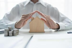 man holding house model with hands on desk. photo