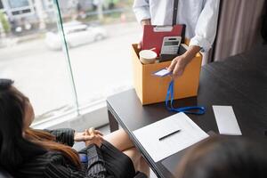 Business man sending Holding Stuff Resign Depress or carrying cardboard box by desk in office. photo