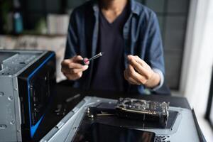 a man is working on a computer with a screwdriver. photo