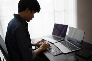 Asian man software engineer Working on Computer at office desk for writing program code IT Software Engineer finding errors tech support devops creating digital. photo