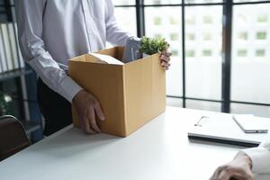 Business man sending resignation letter and packing Stuff Resign carrying business cardboard box Change of job or fired from company resign. photo