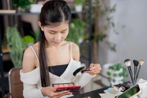 Asian woman applying make up foundation and concealer make up on face with cosmetics Daily routine at home photo